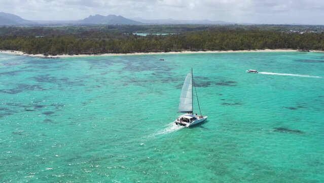 Aerial view of a boat sailing along the shoreline at Ile aux Cerfs and Ilot Mangenie bay, Mauritius Island.
