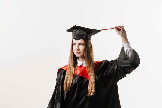 Graduate girl with master degree in black graduation gown and cap on white background. Happy young woman successfully graduated from the university with honors.