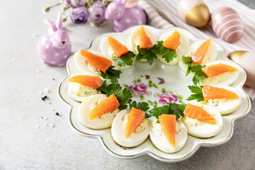 Festive dinner, Easter brunch. Stuffed eggs with cheese and salted salmon in the form of a carrot. Copy space.
