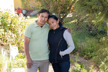 Hispanic couple portrait hugging - Senior adult couple taking a walk in the park - Latin retired...