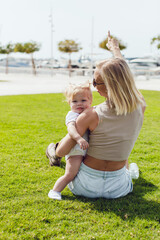 Fototapeta premium A woman with her little daughter are sitting on the grass. Mother and daughter.