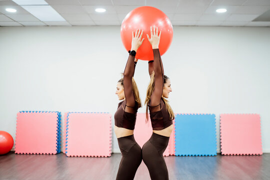 Sporty twin sisters doing pilates in gym