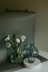 Vase with white  ranunculuses on the table with another vases with background, Still life
