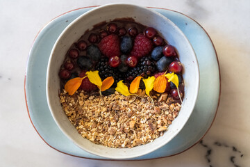 Top view of typical brazilian açaí bowl with cereals, different berries and edible flowers. Healthy breakfast.