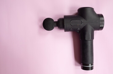 Machine for body massage on pink background. Massage gun. 