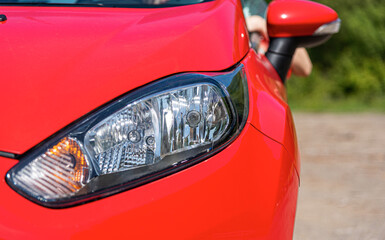 Front and headlight of a red passenger car.