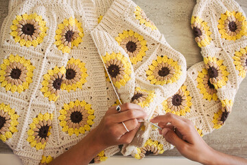 Woman knitting at home cardigan with squares of sunflowers crochet grannys