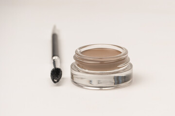 A brow pomade in blonde shade with brush isolated on a white background.
