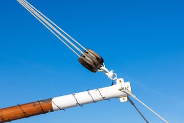 Mast rope and pulley on old sailing boat. Blue sky background