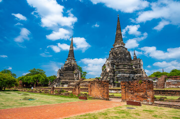 Obraz premium Ruins of ancient city and temples Ayutthaya, Thailand. Old kingdom of Siam. Summer day with blue sky. Famous tourist destination, spiritual place near Bangkok.