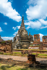 Fototapeta premium Ruins of ancient city and temples Ayutthaya, Thailand. Old kingdom of Siam. Summer day with blue sky. Famous tourist destination, spiritual place near Bangkok.