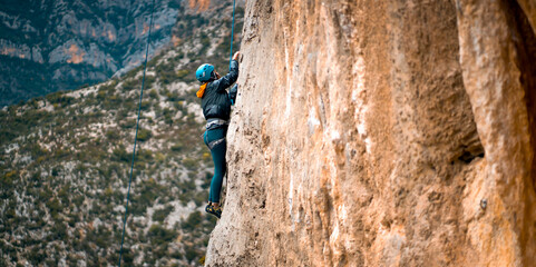 Fototapeta premium A girl is climbing on the rocks in hte mountains.