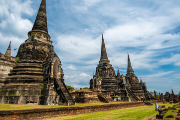 Fototapeta premium Ruins of ancient city and temples Ayutthaya, Thailand. Old kingdom of Siam. Summer day with blue sky. Famous tourist destination, spiritual place near Bangkok.