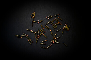 Scattered on a dark surface are bullets, cartridges for a kalashnikov assault rifle.