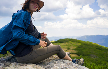 Girl in a hat enjoys her journey, sitting on the rock. © Zhanna