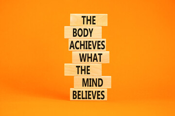 Mind and body symbol. Concept words The body achieves what the mind believes on wooden blocks. Beautiful orange table orange background. Copy space. Motivational mind and body concept.