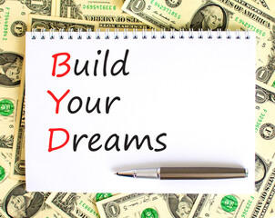 BYD build your dreams symbol. Concept words BYD build your dreams on white note on a beautiful background from dollar bills. Pen. Business and BYD build your dreams concept. Copy space.