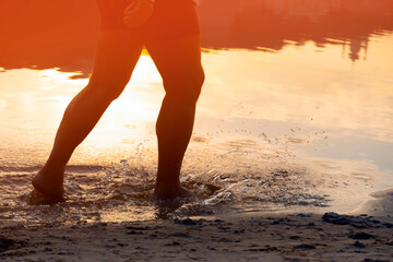 A man is running along the coast, training, legs and water closeup.