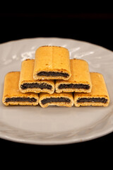 Fig Newton cookies on a white plate on a black background.