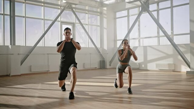Athletic man and woman lunging forward on two leg to strengthen muscles of the thighs and buttocks