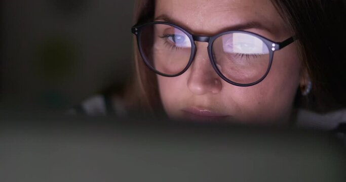 Close up view of focused woman in glasses looking at laptop screen