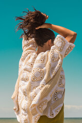 woman on the beach wearing a crochet cardigan made with granny squares, crochet outfit.Outfit spring summer