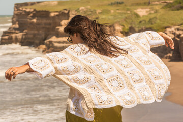 woman on the beach wearing a crochet cardigan made with granny squares, crochet outfit.Outfit...