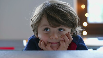 One handsome 2 year old child posing for camera. Closeup face of a cute handsome young boy with hand in chin