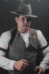 Fototapeta na wymiar American gangster from Chicago. Early 20th century. Hat and formal suit of shirt and vest. Armed with a pistol and a Thompson submachine gun. A dangerous man who solves problems by force.