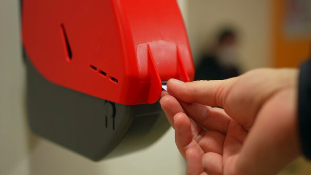 Closeup Of Waiting Number Machine. Customer Hand Pulls A Numbered Ticket In Dispenser Machine. Wait In Service Line