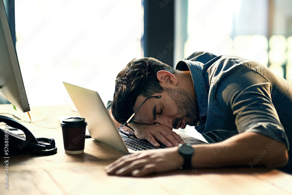 Poster defeated by the deadline. shot of an exhausted young businessman sleeping at his desk during a late 
