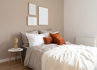 Comfortable double bed with orange piloows, white bedding and blanket in cozy bedroom. Stylish...