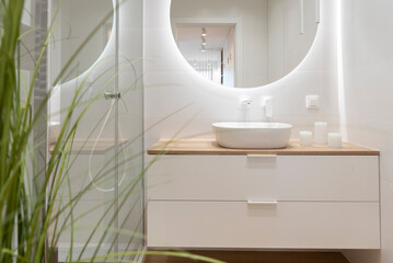 Luxury bathroom with glass to shower, round mirror with led lights, stylish washbasin on wooden...
