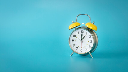 Retro silver alarm clock.  1:00, am, pm. Blue background.