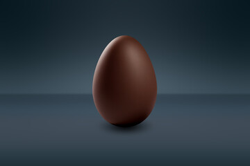 milk chocolate Easter egg in front of a dark wall and on a dark floor