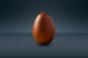 brown chocolate Easter egg in front of a dark wall and on a dark floor