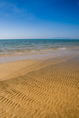 Fototapeta na wymiar Emerald green waves creep onto the sand. The island of Thassos is visible on the horizon.