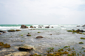 Beautiful tropical landscape. A stone ocean shore with waves and rocks. Beautiful texture background for tourism, design and advertising