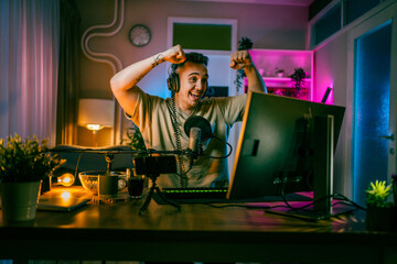 Fototapeta na wymiar Young man male gamer playing computer game streaming video winning