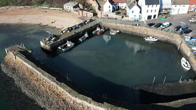 Crail, a historic fishing village on the east coast of Scotland in the East Neuk of Fife. Low level aerial footage of the pretty little harbour. Lovely reflections of whitewashed houses in the water.