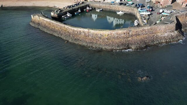 Crail, a historic fishing village on the east coast of Scotland in the East Neuk of Fife. Low level aerial footage of the pretty little harbour. Lovely reflections of whitewashed houses in the water.