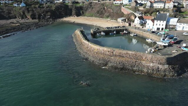 Crail, a historic fishing village on the east coast of Scotland in the East Neuk of Fife. Low level aerial footage of the pretty little harbour. Lovely reflections of whitewashed houses in the water.