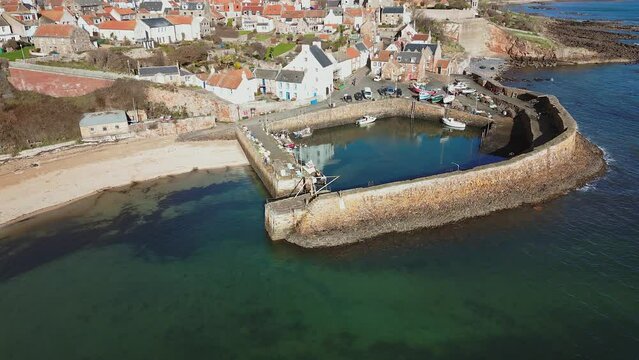 Crail, a historic fishing village on the east coast of Scotland in the East Neuk of Fife. Low level aerial footage of the pretty little harbour. Lovely reflections of whitewashed houses in the water.