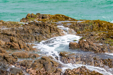 Beautiful tropical landscape. A stone ocean shore with waves and rocks. Beautiful texture background for tourism, design and advertising