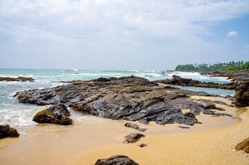 Beautiful tropical landscape. A stone ocean shore with waves and rocks. Beautiful texture background for tourism, design and advertising