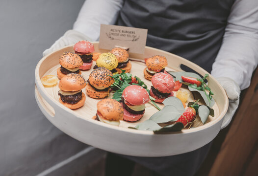 Waiter or waitress hold tray of mini burger canapes