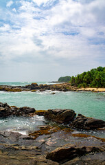 Beautiful tropical landscape. A stone ocean shore with waves and rocks. Beautiful texture background for tourism, design and advertising