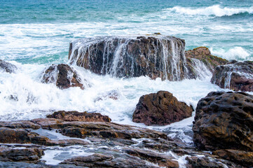 Beautiful tropical landscape. A stone ocean shore with waves and rocks. Beautiful texture background for tourism, design and advertising