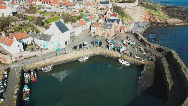 Crail, a historic fishing village on the east coast of Scotland in the East Neuk of Fife. Low level aerial footage of the pretty little harbour. Lovely reflections of whitewashed houses in the water.