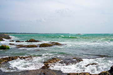 Beautiful tropical landscape. A stone ocean shore with waves and rocks. Beautiful texture background for tourism, design and advertising